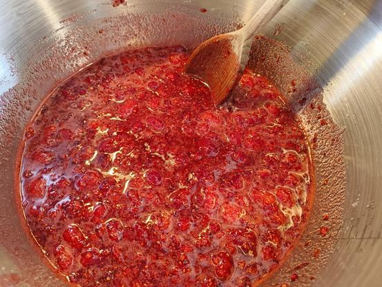 Raspberry jam boiling in a jam kettle.