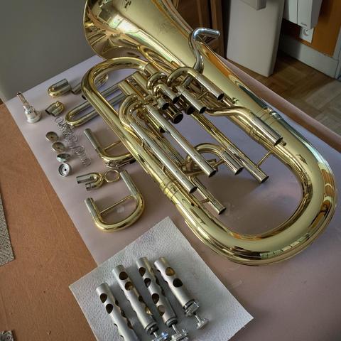 Un euphonium entièrement démonté posé sur une table. C’est plein de tuyaux dorés, de petites pièces, de ressorts, de pistons.