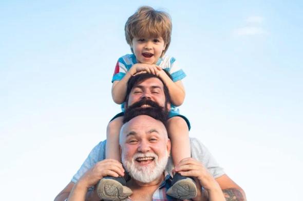 PORTUGUÊS :
Três gerações de uma família compartilham um momento alegre ao ar livre sob um céu azul claro. Um homem mais velho, sorridente e de barba branca, carrega nos ombros um homem de meia-idade com barba, que por sua vez carrega um menino risonho. Os três parecem felizes e relaxados.

ENGLISH:

Three generations of family share a joyful moment outdoors under a clear blue sky. A smiling older man with a white beard carries a bearded middle-aged man on his shoulders, who in turn carries a laughing young boy. All three look happy and relaxed.

FRANÇAIS:
Trois générations d’une famille partagent un moment de joie en plein air sous un ciel bleu clair. Un homme plus âgé, souriant et portant une barbe blanche, porte sur ses épaules un homme barbu d’âge moyen, qui porte à son tour un jeune garçon souriant. Les trois semblent heureux et détendus.