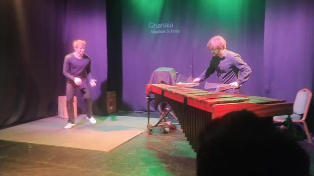 A man in tap dance shoes and another playing a marimba in stage
