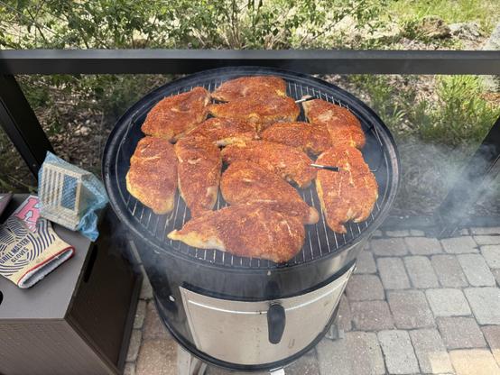 Action shot of a bunch of boneless skinless dry-rubbed chicken breasts on a 22-inch Weber Smokey Mountain grill.