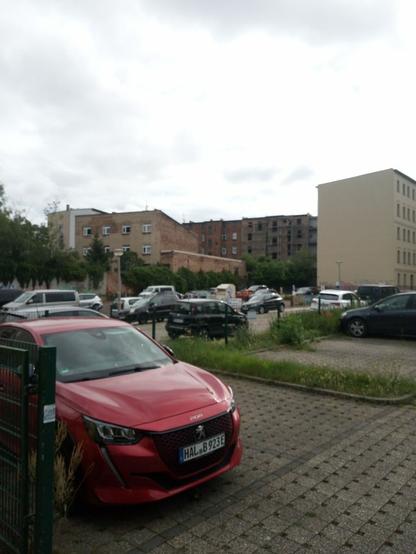 Ein Parkplatz aus Rasenpflastersteinen, ohne Rasen in den Pflastersteinen. Kleine Grünstreifen. Autos.