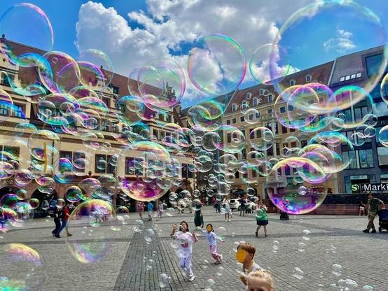 Viele Seifenblasen auf dem Leipziger Marktplatz. Ein Clown mit Profi-Equipment hat sie wehen lassen, zur Freude vieler Kinder.
Sommersonne, blauer Himmel mit weißen Wolken.
Mitte Juli 2025
