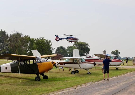 Theda Star medical helicopter landing in the background. Several high wing aircraft parked on the flight line in the foreground.