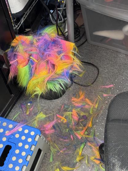 Rainbow fur clipping filling a trash bin and on the floor