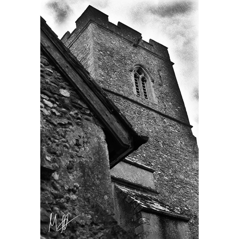 A low angle shot of a church bell tower and it's parapets in black and white