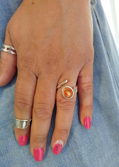 A silver ring with an orange gemstone, wear on woman's hand