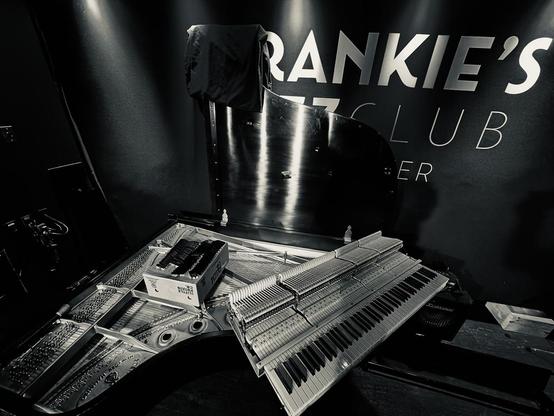 A black and white photograph of a grand piano being taken apart. Backstage at Frankie’s Jazz Club in Vancouver.