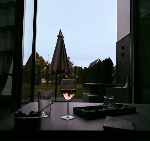 Ein niedriger Tisch mit Snacks, einem Glas Wein & einem eReader steht vor der offen Terrassentür