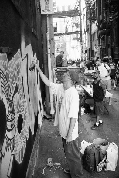 In a dark alley people watch artists at work.