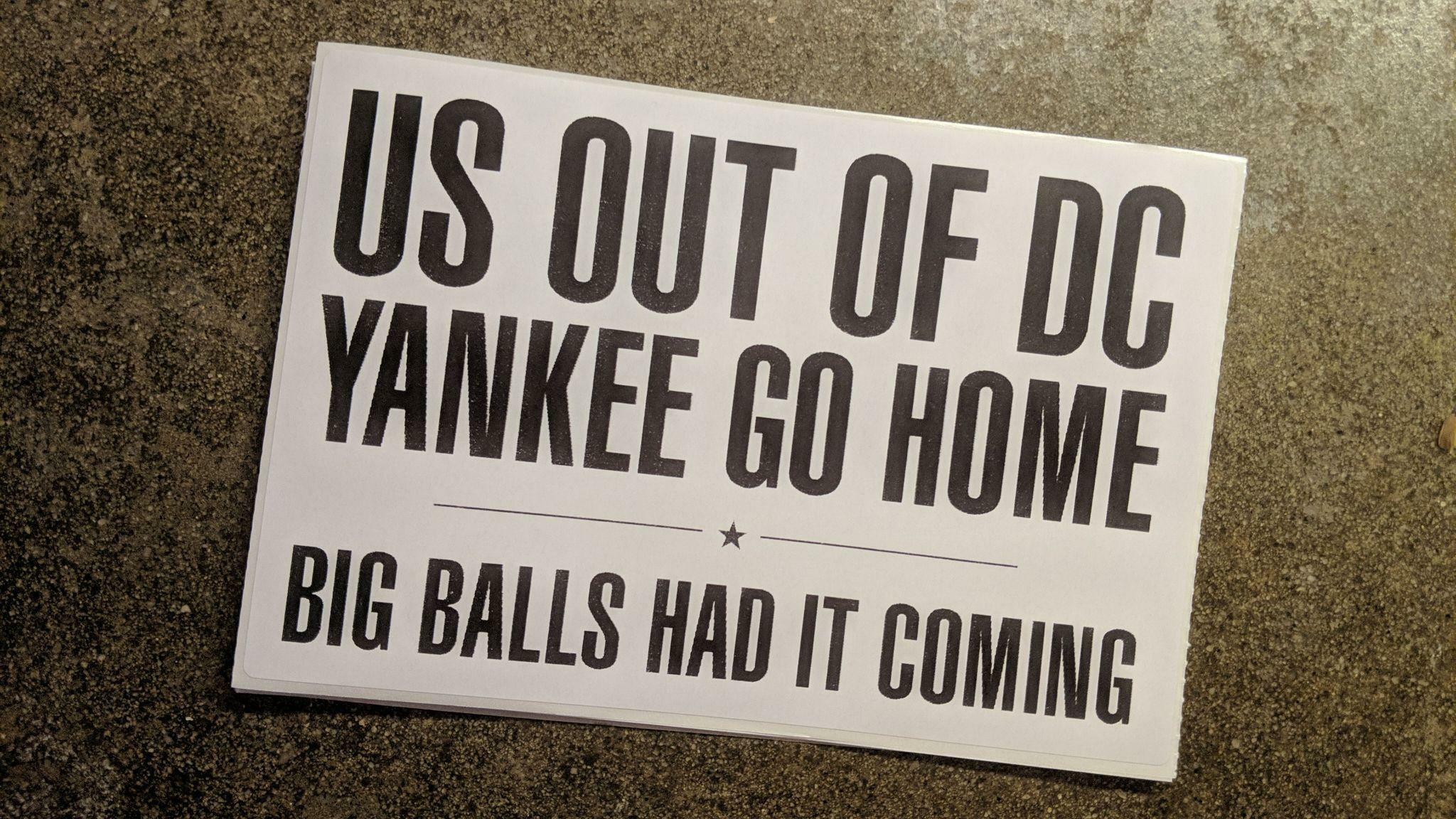 A 4x6 thermal printed sticker on a concrete background. The sticker reads US OUT OF DC; YANKEE GO HOME; BIG BALLS HAD IT COMING