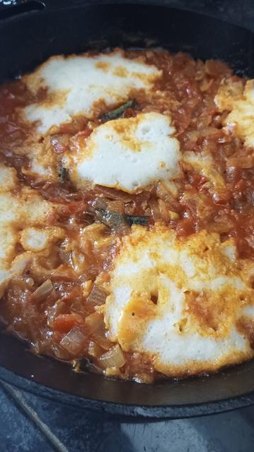 Close up showing the onion and tomato base and the cooked idli.