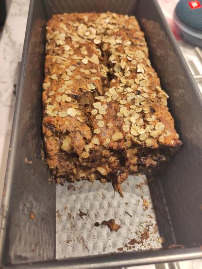 Banana bread in a container. A piece has already been cut out.