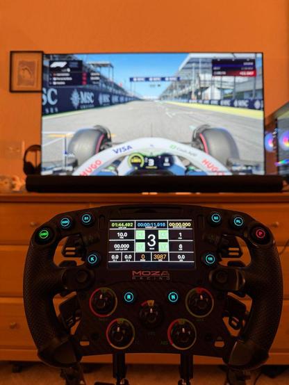 A Moza FSR2 wheel all lit up in front of a TV with a Racing Bulls car.