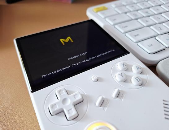 Closeup of a white RG40XXV on a beige desk, next to a white keyboard with a yellow accent key.

The screen is showing the MuOs initial setup screen, with a yellow M, and the analog stick is lit up yellow.

The colour coordination is completely accidental and yellow is far from my favourite colour 😂