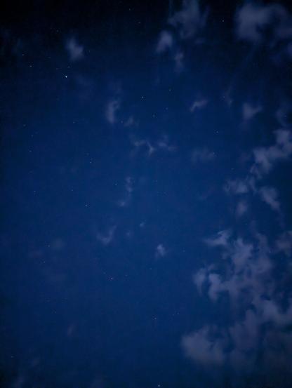 Nachthimmel mit vereinzelten Wolken und vielen kleinen Sternen.
