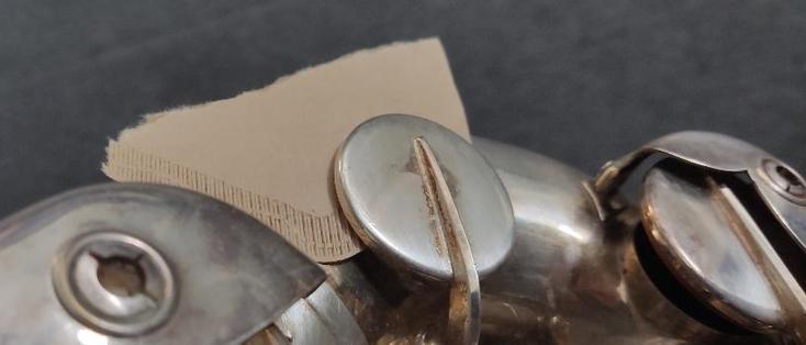 Ein Teil eines Saxophons ist zu sehen.
Unter einer der Klappen klemmt ein Stück Kaffefilterpapier.