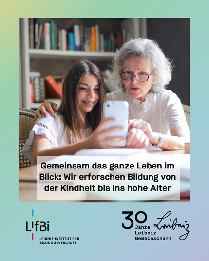 Junges Mädchen und ältere Frau sitzen gemeinsam am Tisch. Vor ihnen liegen Bücher. Sie blicken auf ein Smartphone in der Hand des Mädchens.