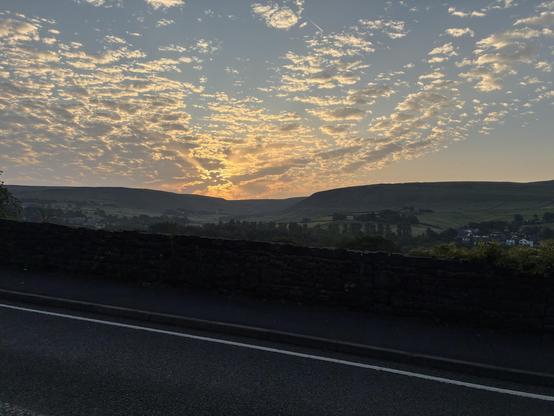A scenic landscape at sunrise, showcasing a vibrant sky filled with clouds and warm colors.