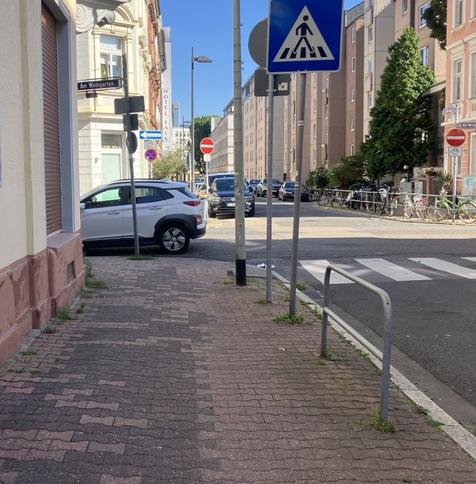 Blick entlang eines Fußwegs, im Kreuzungsbereich steht ein leeres Auto