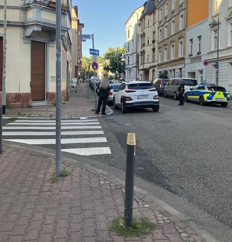 Die gleiche Stelle aus einer anderen Perspektive, aber mit Polizeiauto daneben und zwei Menschen in Uniform am Auto
