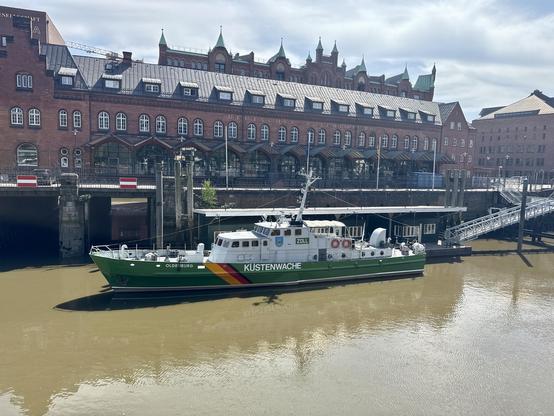 Dark red brick buildings at a canal at the Speicherstadt. This one is the old customs office with an old customs ship.