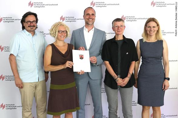 Wissenschaftsminister Clemens Hoch (Mitte) übergibt den Förderbescheid für das Projekt "PRO.SOZIAL" an der Hochschule für Wirtschaft und Gesellschaft Ludwigshafen an die Antragstellerinnen Prof. Dr. Marion Ott (2.v.l.) und Prof. Dr. Karen Wagels (2.v.r.) im Beisein von Dekan Prof. Dr. Peter Rahn und Vizepräsidentin Prof. Dr. Edith Rüger-Muck (Foto/©: Antonia Zwicker / HWG LU)