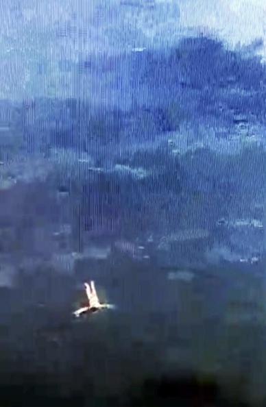 Unscharfes Bild einer Person, die auf dem Rücken im Wasser treibt, mit bläulichem Himmel und Wasser im Hintergrund.