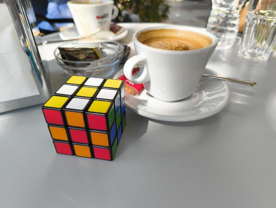 Cub de Rubik al costat d'un cafè amb llet a la taula de la terrassa d'un bar.