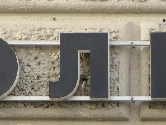 Чёрная буква Л на фасаде тяжело декорированного дома. // A black L on the facade of a heavily decorated house.