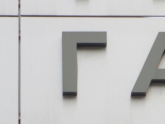 Серая буква Г на светло-металлическом фасаде молла. // A grey G on the light metallic facade of a mall.