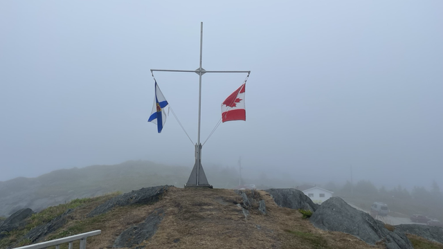 Nova Scotia flag and Maple Leaf of Canada flying in fog.