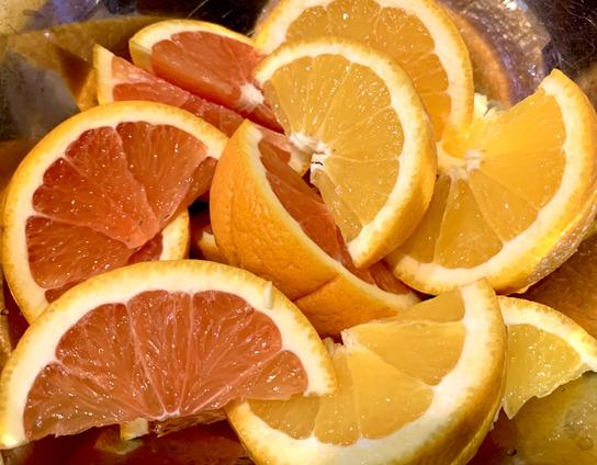 A bowl filled with sliced Cara Cara navel oranges, which are darker in color, and regular navel oranges that have lighter color.