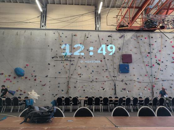Visitor counter at Evoke demo party, projected onto a climbing wall. The counter says 0, the clock above 12:49.