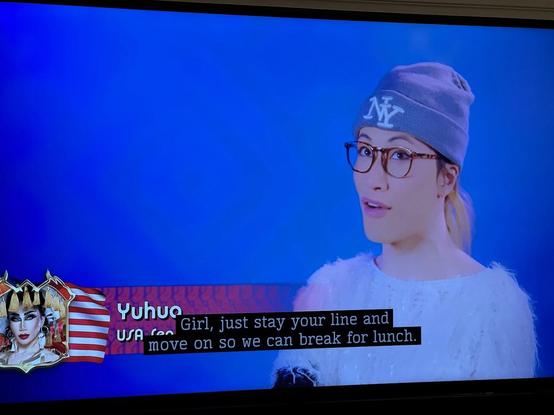 In the Slaysian Royale confessional, Yuhua, wearing a blue Yankees wool cap, glasses and a white textured top, looks at the camera and says "Girl, just say your line and move on so we can break for lunch."