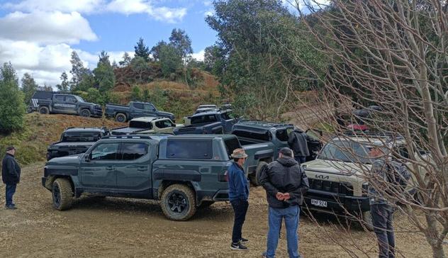 A fleet of Kia Tasman pick-ups on a muddy track in Otaki, New Zealand.