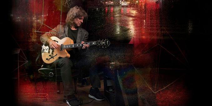 Pat Metheny with his yellow jazz guitar, on a red and black background.