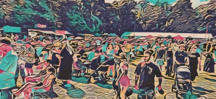 Photo of some of the crowd on the field, with food and drink vendor stalls around the outer. A large arts and crafts marquee at the back. Off camera to the right is the large food tent. Off to the left is the stage, where lots more people were led on the grass. Photo has an arty effect to preserve privacy as the photo shows some people in detail.