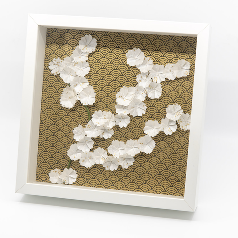 Photo d’un tableau d’une branche en origami avec des fleurs blanches sur fond noir et or