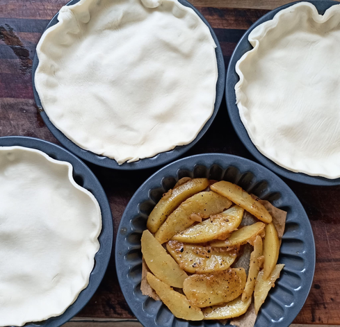 4 kleine Tarte-förmchen, 3 sind schon mit Teig bedeckt, eines noch nicht, darin sieht man die Kartoffeln.