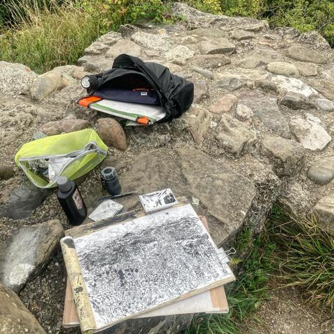 Foto einer Tasche , diverser Zeichenuntensilien und der auf ein Brett geklemmten Zeichnung (siehe erstes Bild im Beitrag)