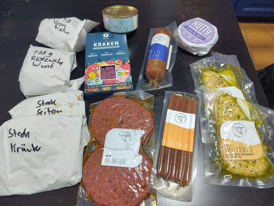Gekaufte Produkte auf schwarzen Tisch, teilweise verpackt in weißen neutralen Papier oder in  Plastik verschweißt.