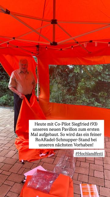 Mein Vater steht in einem orangefarbenen Pavillon und hält die Zeltbahn für eine Seitenwand
