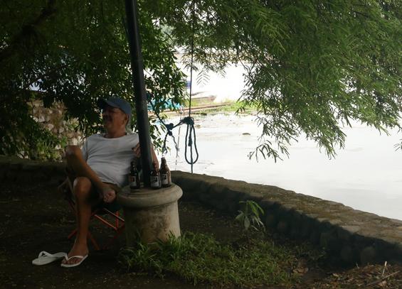 2/4
A man relaxing by the lakeside, bottles of San Miguel by his side, talking to a buddy across him (out of frame).