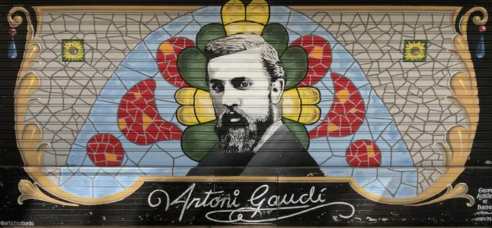 A colorful mural depicting Antoni Gaudí, featuring a black and white portrait of him surrounded by floral patterns in vibrant colors. The name Antoni Gaudí is elegantly scripted below the image.