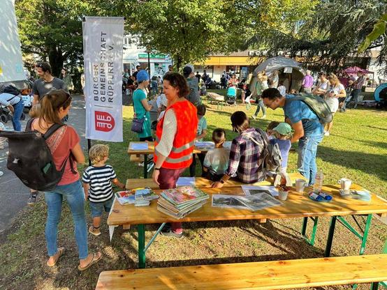 Foto von dem Stand der BGR bei Karlsruhe spielt aus dem Jahr 2024. Es sind Bierbänke auf der Wiese vor der katholischen Kirche in Rüppurr zu sehen. Kinder sitzen auf den Bänken und malen.