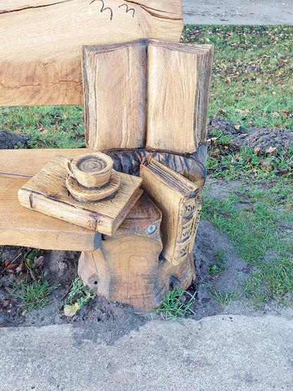 Eine Sitzbank aus Holz  mit geschnitzten Büchern und Tasse