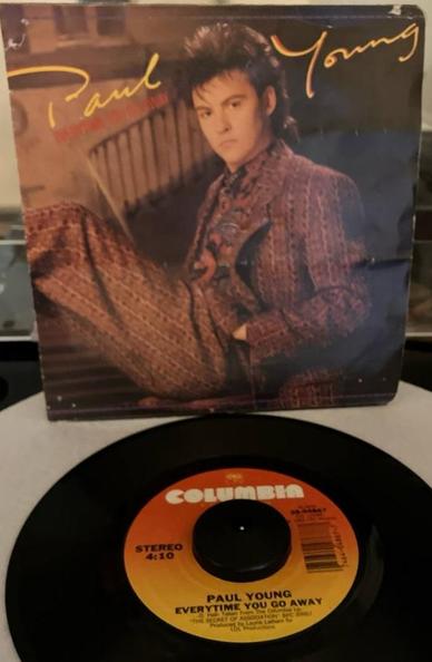 A 45rpm picture sleeve above a record on a turntable. Sleeve features a seated man in a patterned suit with his hands in his pockets and feathered hair.  Around him is "Paul Young" in a signature like font.

Below is a record label that shades from orange to yellow, top to bottom. Above the spindle hole in block letters is "Columbia". To the left is "Stereo" and "4:10", the right a bar code.  Underneath the spindle hole is "Paul Young" "Everytime You Go Away".