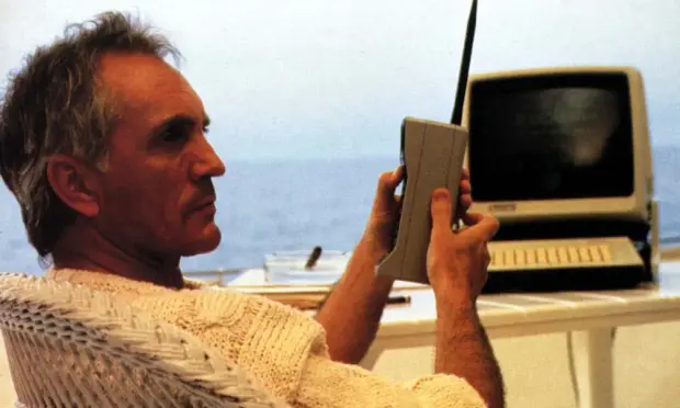 Terence Stamp in character on a yacht with a brick sized phone and a computer with chunky keys, 1987.