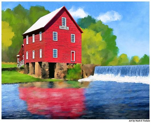 A bright red  historic grist mill sitting alongside a stream and manmade dam. Green grass and brilliant blue skies. The water is reflecting parts of the mill and the blue sky.